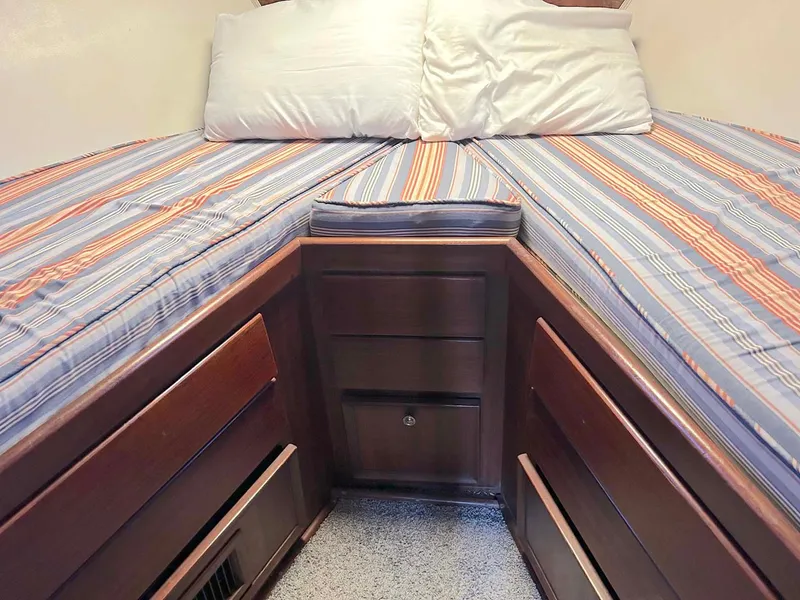 Slide: The Image of Cozy cabin interior of 1975 Hatteras 36 Convertible with striped bedding and wooden storage. - 22