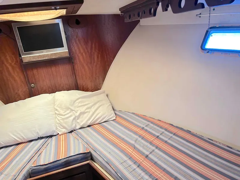 Slide: The Image of Cozy cabin interior of 1975 Hatteras 36 Convertible with striped bedding and a small TV. - 23