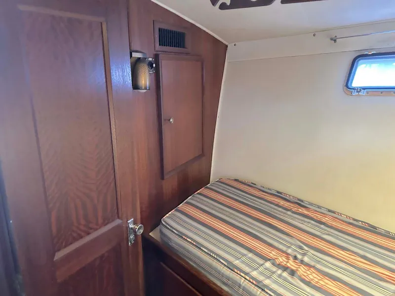 Slide: The Image of 1975 Hatteras 36 Convertible cabin interior with striped bedding and wooden paneling. - 25