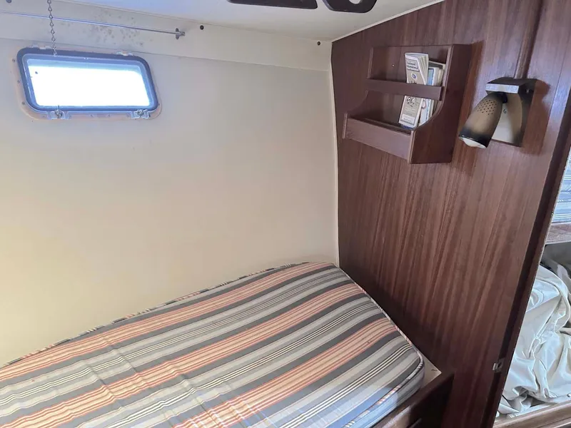 Slide: The Image of 1975 Hatteras 36 Convertible cabin with striped bedding and wooden shelves. - 26