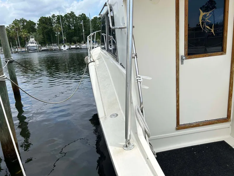 Slide: The Image of 1975 Hatteras 36 Convertible yacht docked at marina, side view with water and trees. - 32