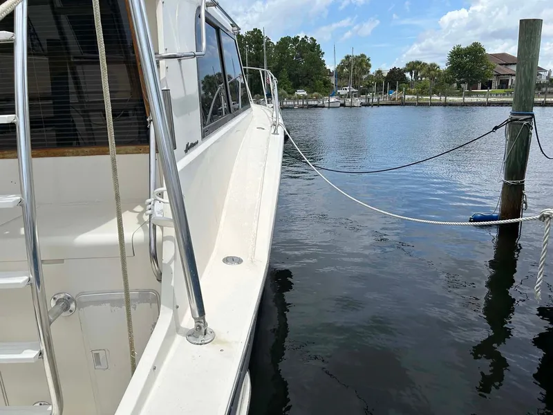 Slide: The Image of 1975 Hatteras 36 Convertible yacht docked by a serene waterfront. - 33