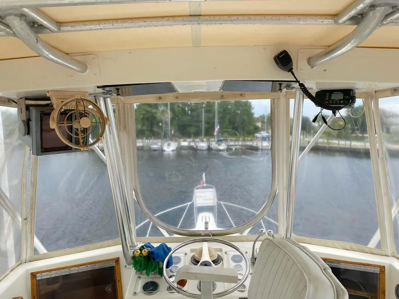 Slide: The Image of Interior view of 1975 Hatteras 36 Convertible boat cockpit with steering wheel and marina view. - 42