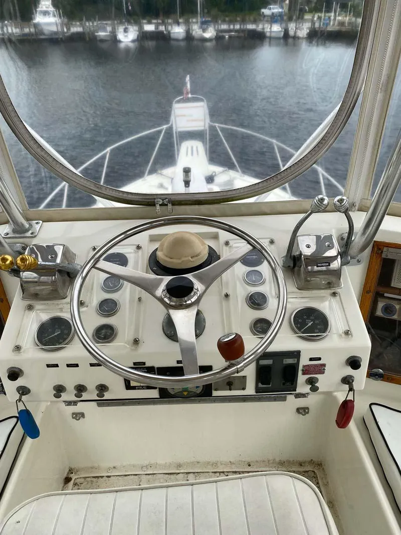 Slide: The Image of 1975 Hatteras 36 Convertible helm with steering wheel and control panel, overlooking marina. - 43