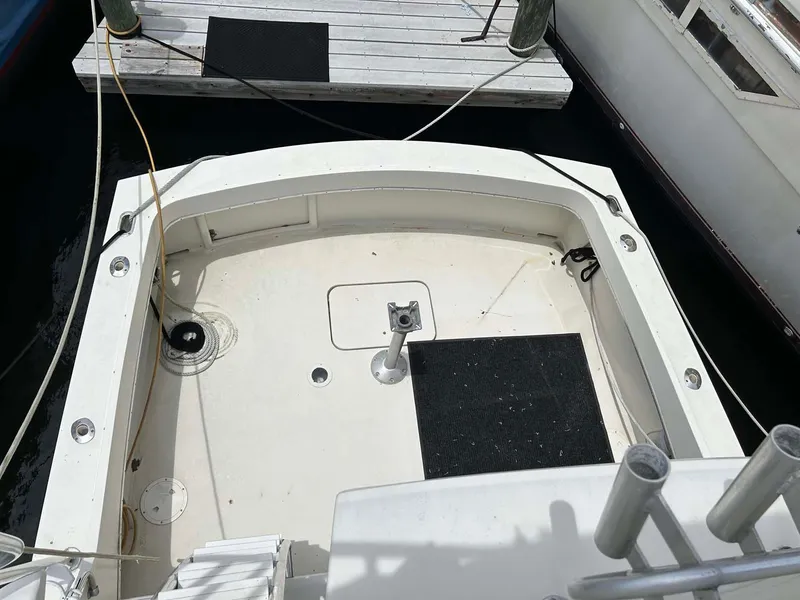 Slide: The Image of 1975 Hatteras 36 Convertible boat deck, docked, with clean white surface and black mats. - 6