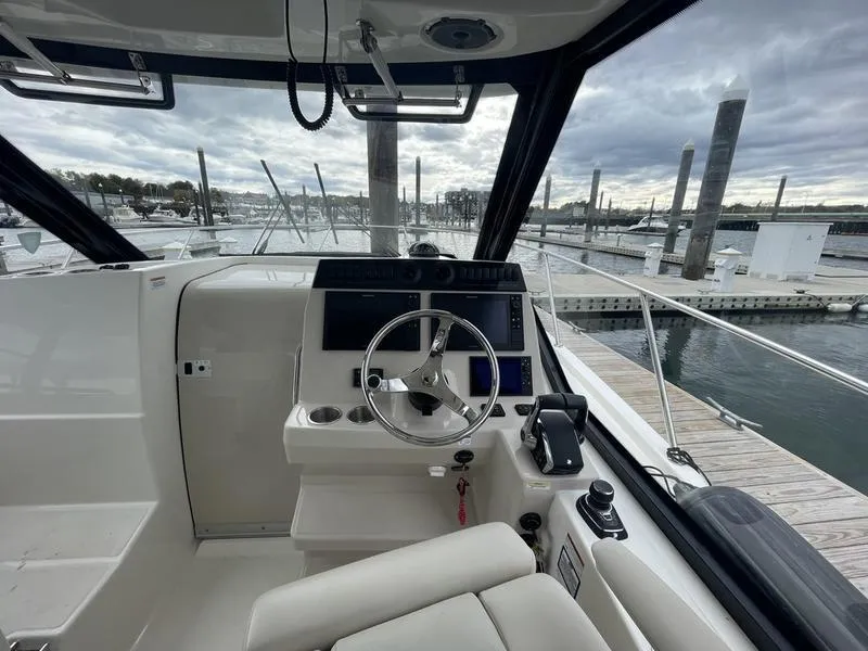 Slide: The Image of 2023 Boston Whaler 325 Conquest helm, docked at marina with overcast sky. - 10