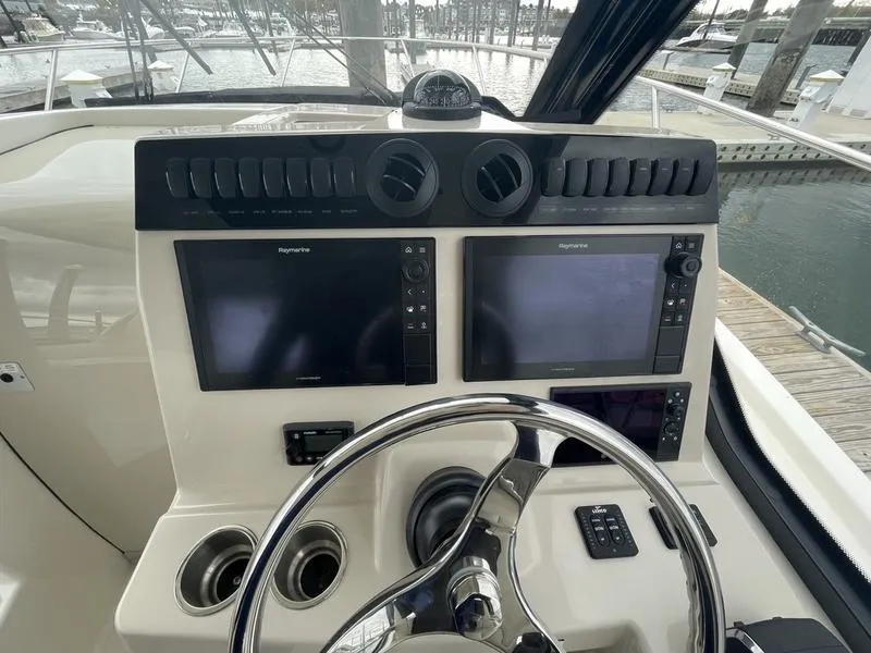 Slide: The Image of 2023 Boston Whaler 325 Conquest helm with dual Raymarine displays and steering wheel. - 12