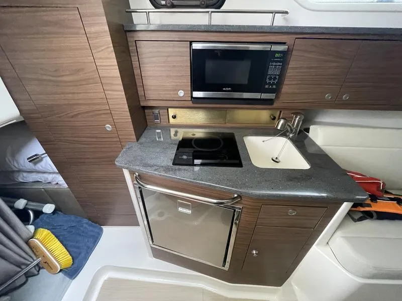Slide: The Image of 2023 Boston Whaler 325 Conquest galley with microwave, sink, and compact fridge. - 14