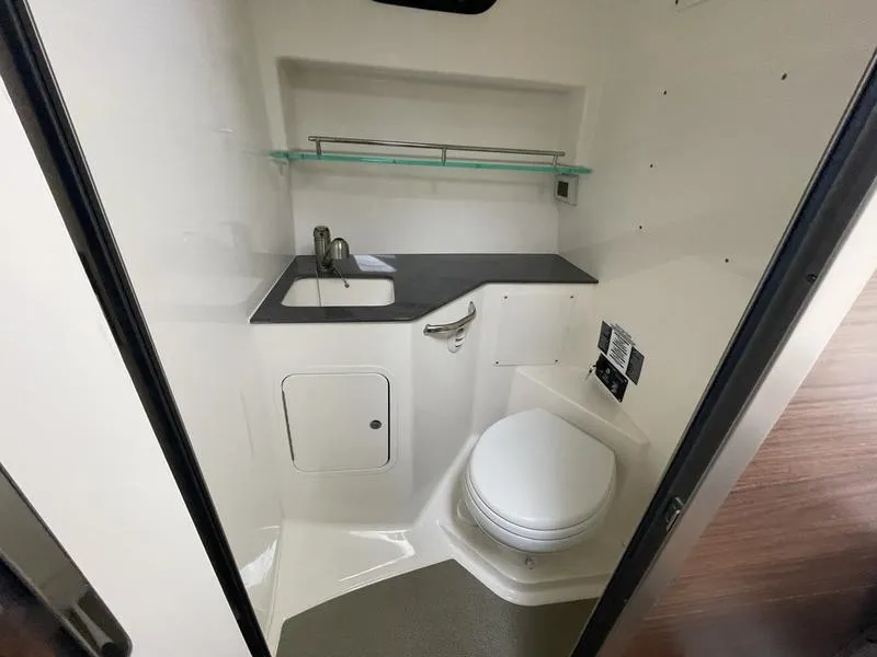 Slide: The Image of 2023 Boston Whaler 325 Conquest bathroom with sink, toilet, and storage shelf. - 15