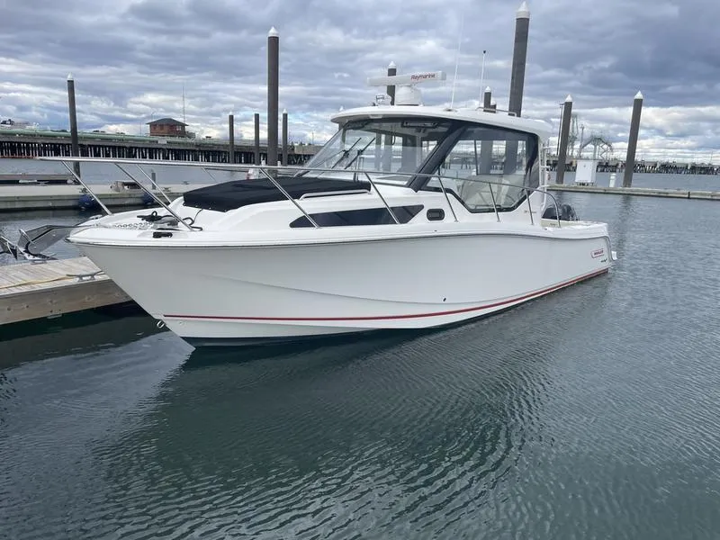 Slide: The Image of 2023 Boston Whaler 325 Conquest boat docked in marina under cloudy sky. - 2