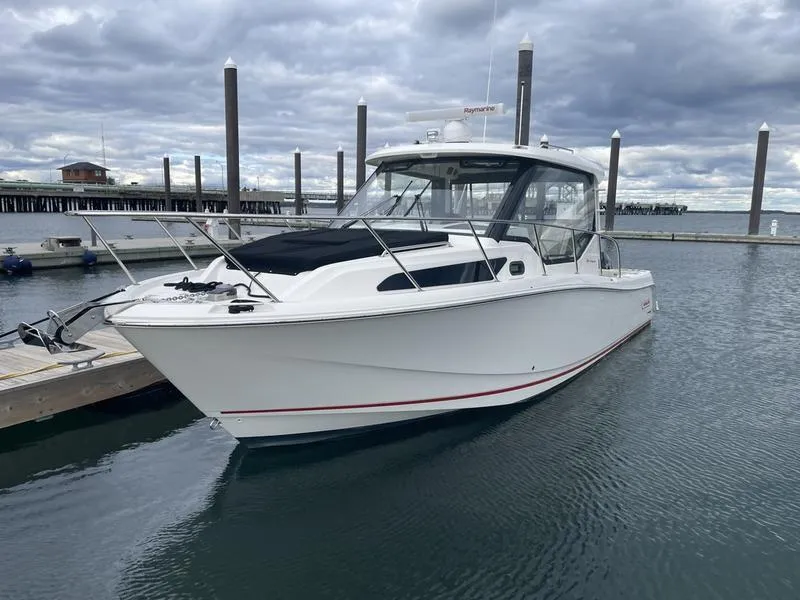 Slide: The Image of 2023 Boston Whaler 325 Conquest boat docked in a marina under cloudy skies. - 3