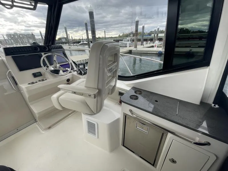 Slide: The Image of Interior of 2023 Boston Whaler 325 Conquest boat, featuring helm and kitchenette area. - 8