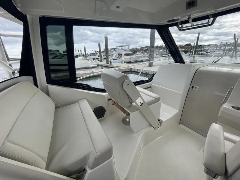 Slide: The Image of Interior of 2023 Boston Whaler 325 Conquest boat, featuring sleek seating and marina view. - 9