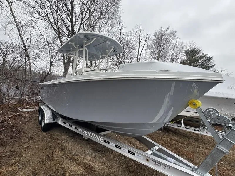 Slide: The Image of 2025 Parker 23 SE CC boat on trailer, parked outdoors, surrounded by trees. - 1