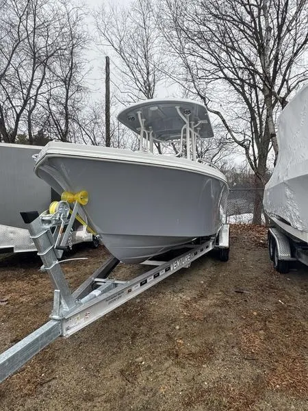 Slide: The Image of 2025 Parker 23 SE CC boat on trailer, parked outdoors, surrounded by trees. - 2