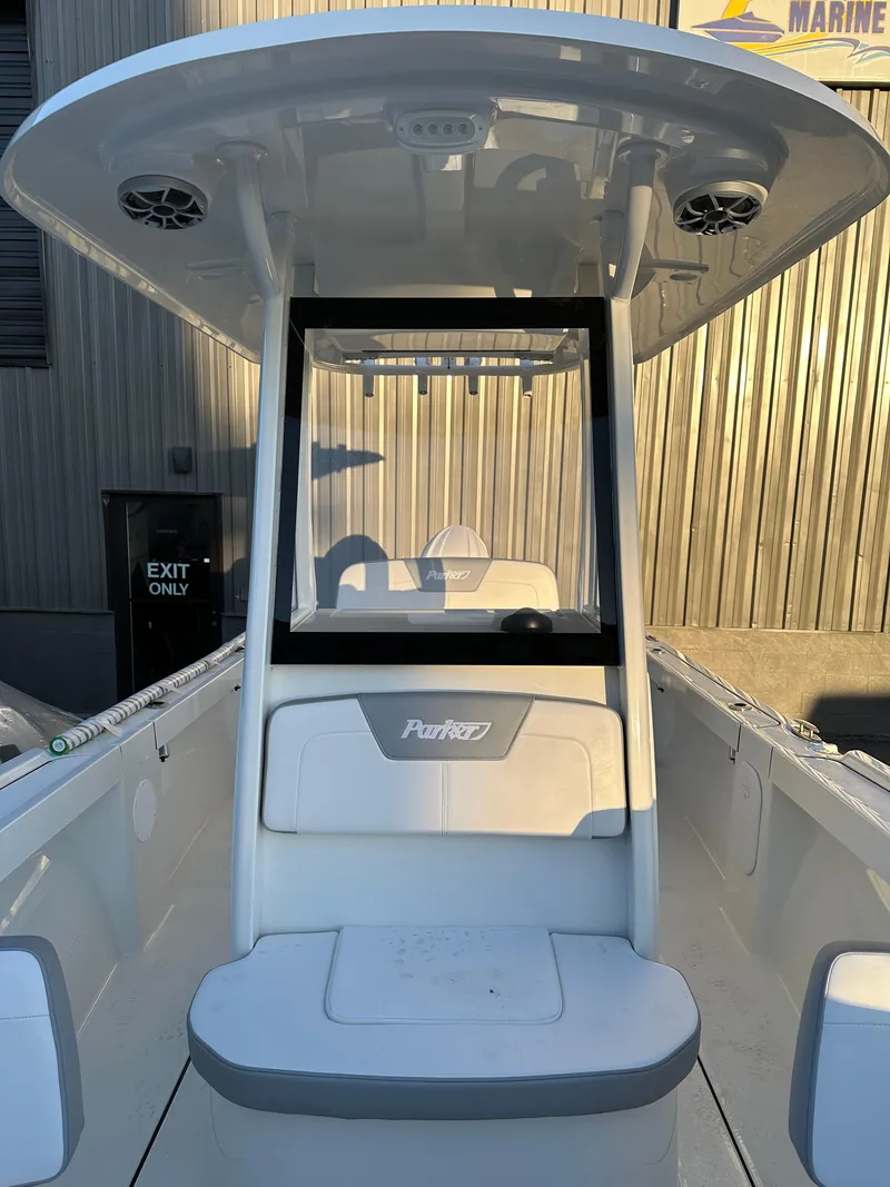 Slide: The Image of 2025 Parker 2200 CC boat with T-top and center console, docked near a marine facility. - 20