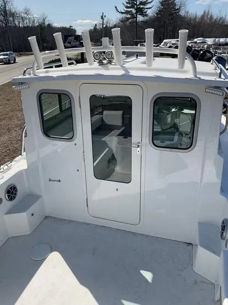 Slide: The Image of 2025 Parker 2120 Sport Cabin boat, rear view with rod holders and cabin door. - 11