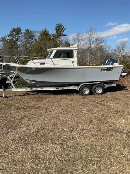 Slide: The Image of 2025 Parker 2120 Sport Cabin boat on trailer, parked on grass, under clear blue sky. - 4