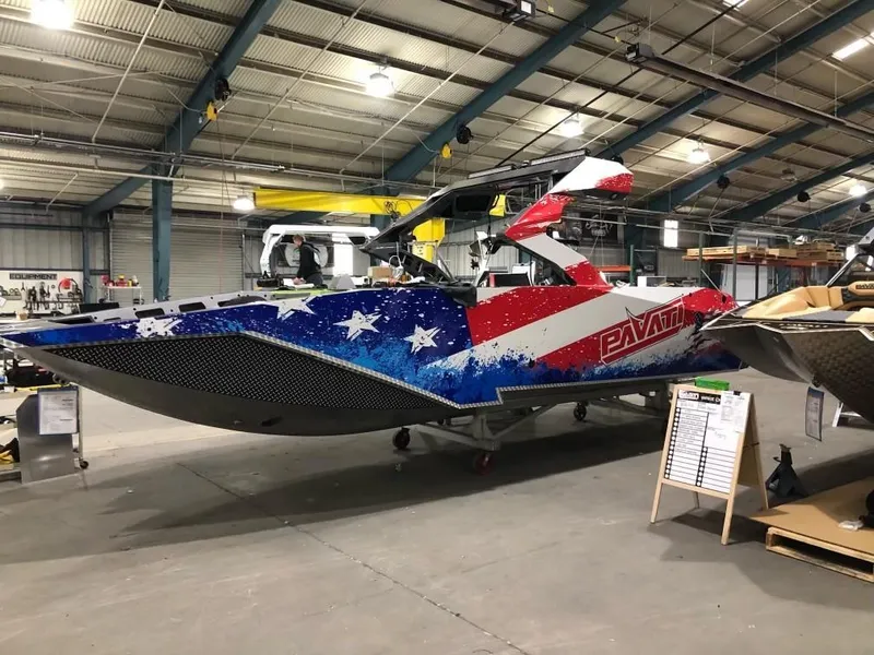 Slide: The Image of 2022 Pavati AL26 boat with American flag design in a warehouse. - 0