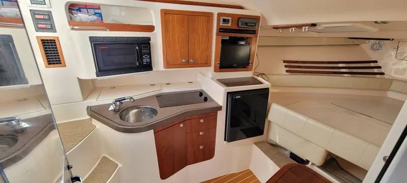Slide: The Image of 2008 Grady-White 330 Express cabin interior with kitchenette and seating area. - 10