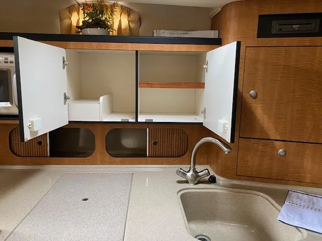 Slide: The Image of 2006 Sea Ray Sundancer kitchen with open cabinets and sink. - 11