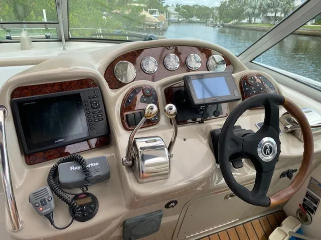 Slide: The Image of 2006 Sea Ray Sundancer helm with navigation equipment and steering wheel, overlooking a serene waterway. - 23