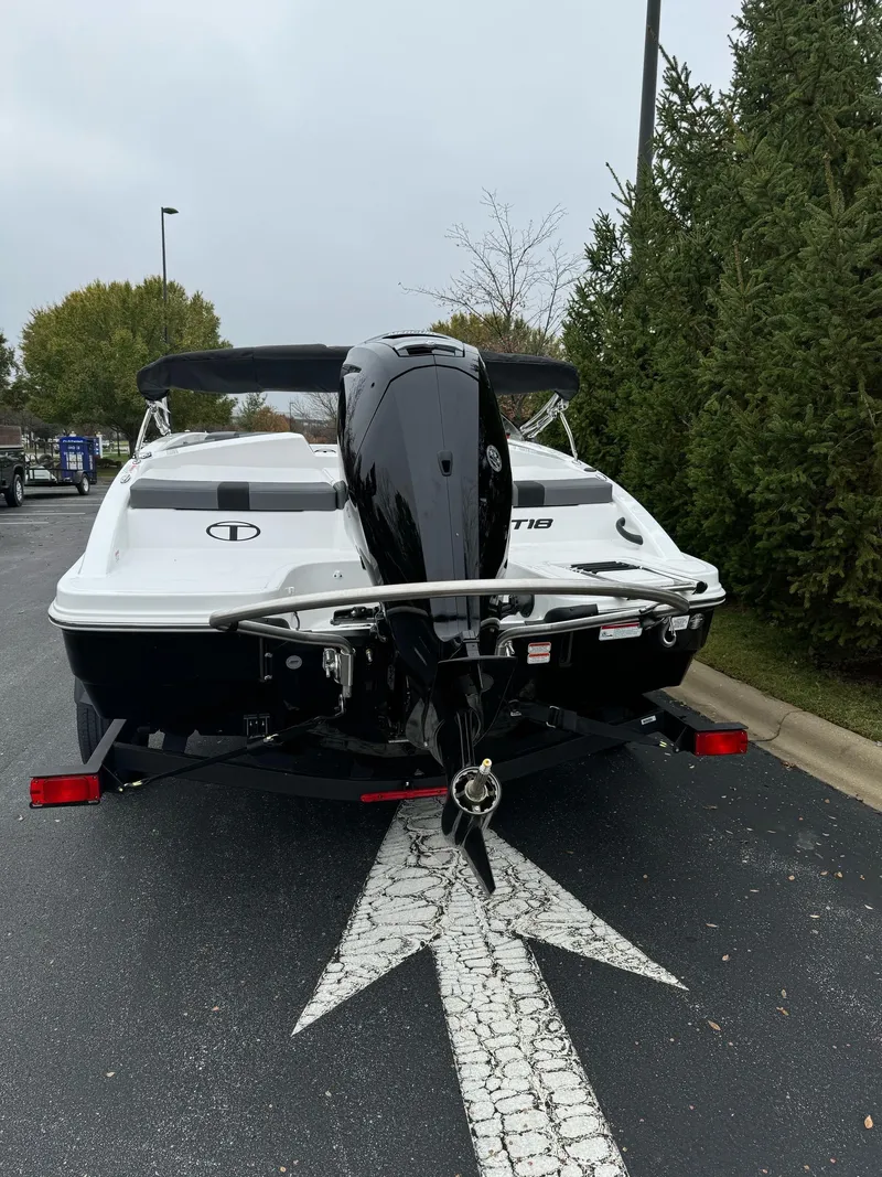Slide: The Image of 2025 Tahoe T18 boat, rear view, parked on asphalt near trees. - 5