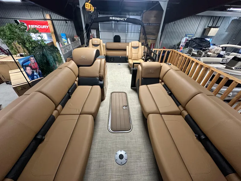 Slide: The Image of 2025 Regency 250 LE3 Sport pontoon boat interior with tan seating in showroom. - 11