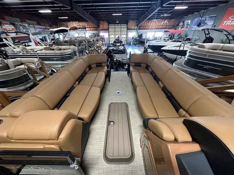 Slide: The Image of 2025 Regency 250 LE3 Sport pontoon boat interior with tan seating in showroom. - 12