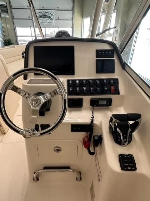 Slide: The Image of 2024 Grady-White 255 FREEDOM boat dashboard with steering wheel and control panel. - 7