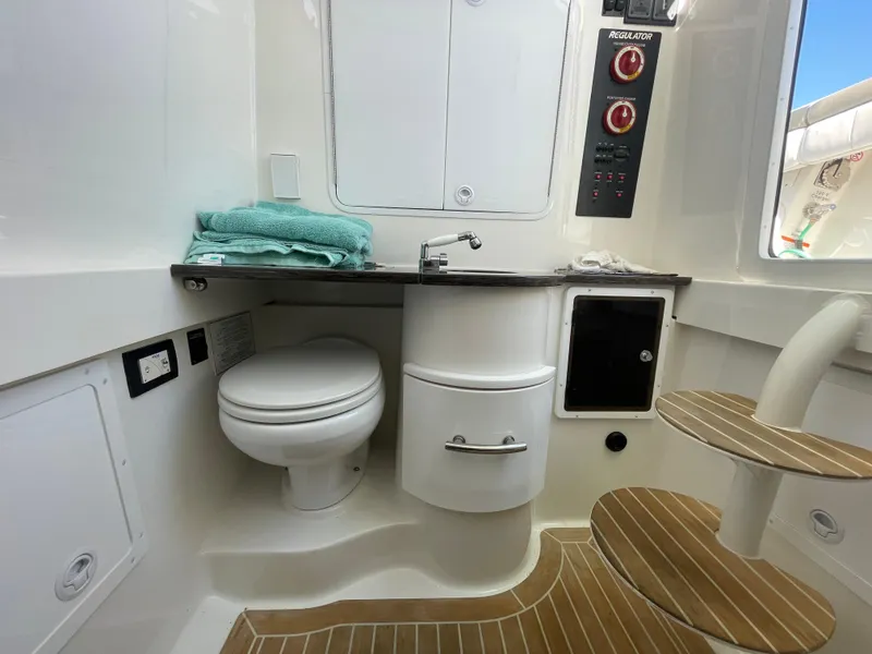 Slide: The Image of 2019 Regulator 34 boat interior with toilet, sink, and wooden steps. - 21