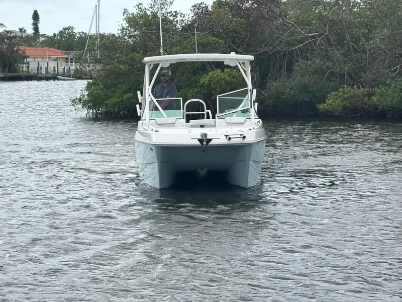 Slide: The Image of 2025 World Cat 230 SD boat navigating a calm waterway with lush greenery. - 1