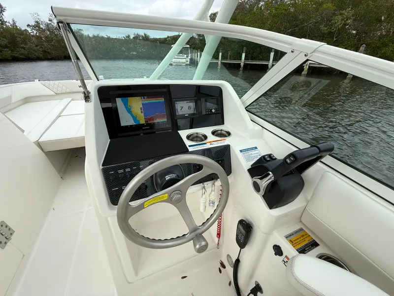 Slide: The Image of 2025 World Cat 230 SD boat cockpit with steering wheel, navigation system, and controls. - 13