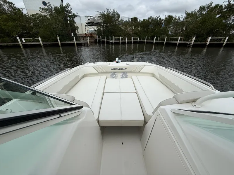 Slide: The Image of 2025 World Cat 230 SD boat interior with white seating, docked by a calm waterway. - 15