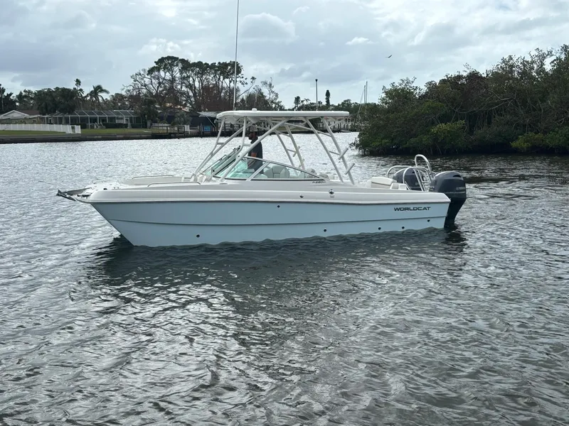 Slide: The Image of 2025 World Cat 230 SD boat on calm water, overcast sky, lush shoreline. - 3
