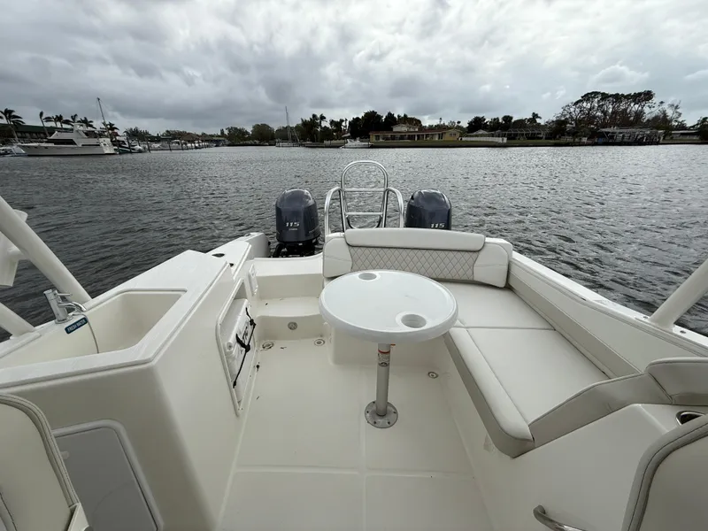 Slide: The Image of 2025 World Cat 230 SD boat interior with seating and table, overlooking a calm waterfront. - 8