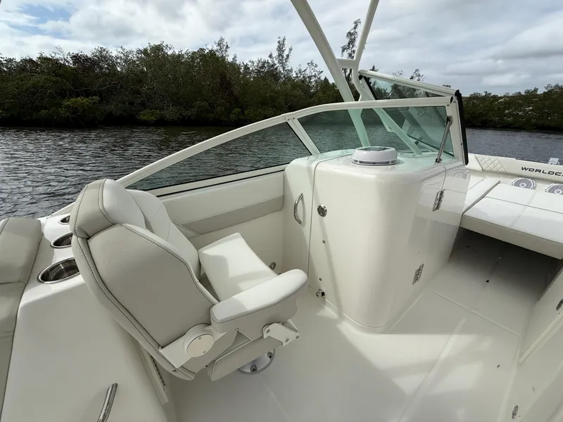 Slide: The Image of 2025 World Cat 230 SD boat interior with white seating and console, near water and trees. - 9