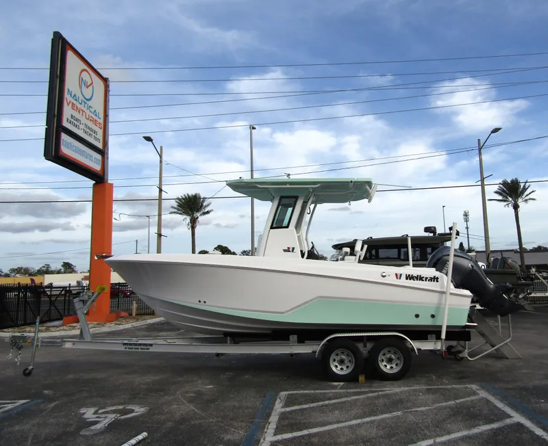 Slide: The Image of 2025 Wellcraft 223 Fisherman boat on trailer at dealership, clear sky background. - 0