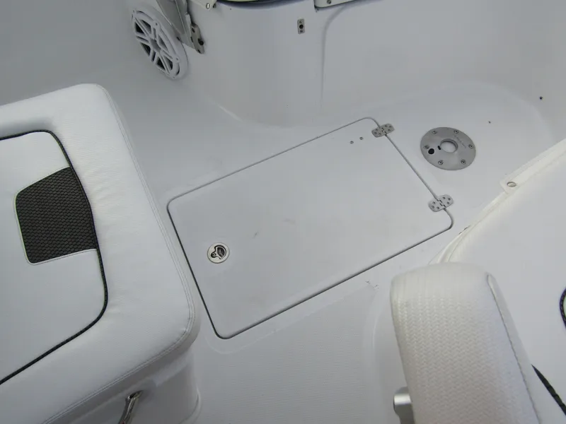 Slide: The Image of 2025 Wellcraft 223 Fisherman boat interior, featuring white seating and storage compartment. - 12