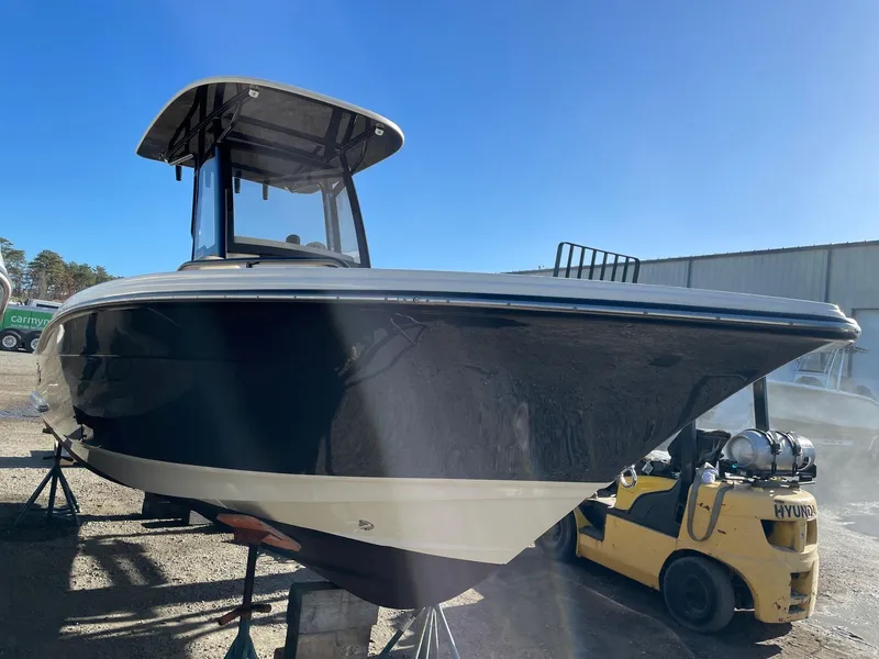 Slide: The Image of 2023 Scout 215 XSF boat on display outdoors, clear blue sky background. - 2