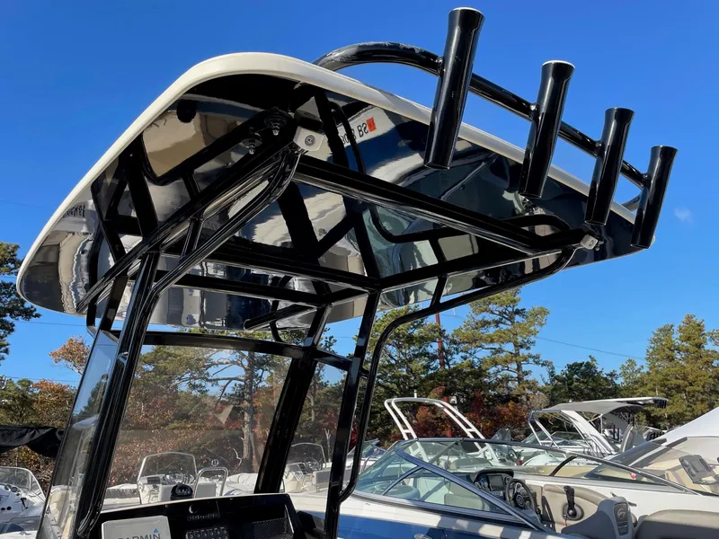 Slide: The Image of 2023 Scout 215 XSF boat with T-top and rod holders, under clear blue sky. - 7