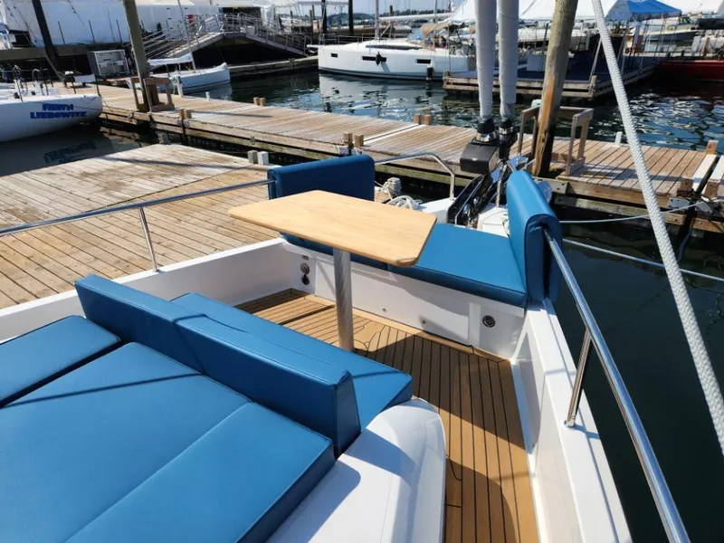 Slide: The Image of Luxurious Moody 48 DS yacht deck with blue seating and wooden table, docked at marina. - 10
