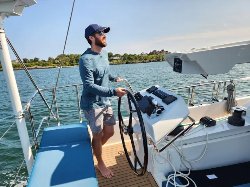 Slide: The Image of Man steering a 2025 Moody 48 DS yacht on a sunny day. - 36