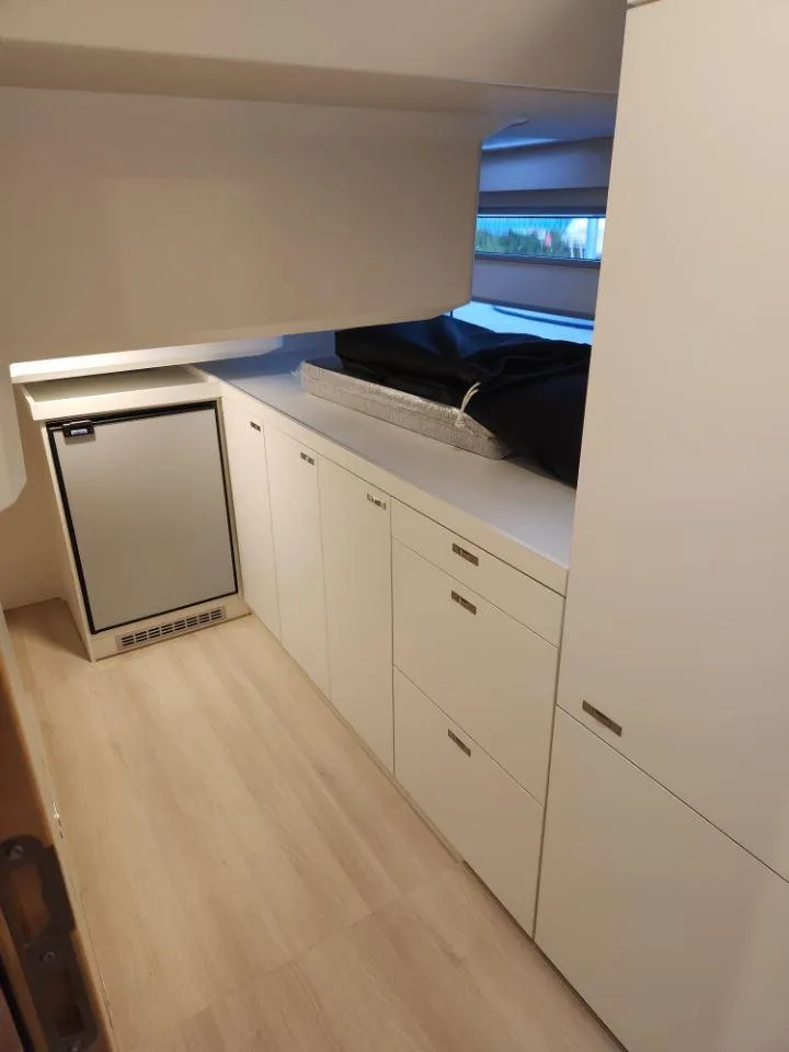 Slide: The Image of Modern interior of 2025 Moody 48 DS yacht with sleek cabinetry and compact fridge. - 49