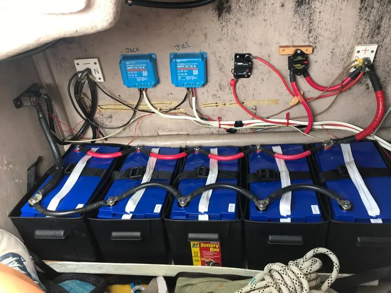Slide: The Image of Battery setup in a 1984 Beneteau First 42 sailboat, featuring multiple blue batteries and wiring. - 22