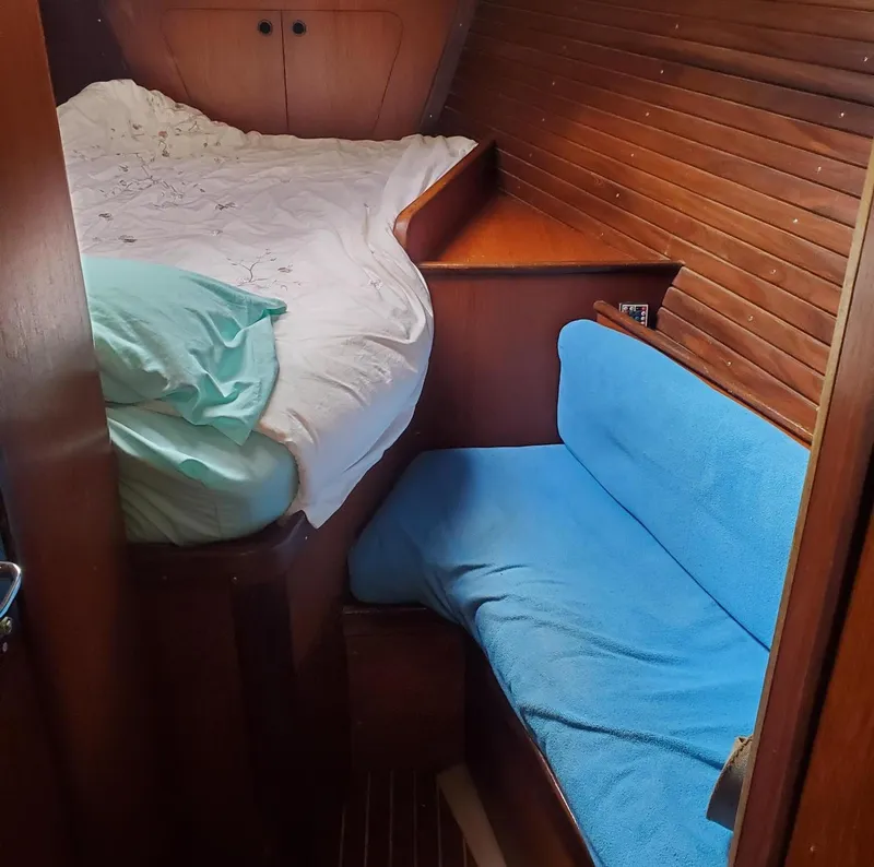 Slide: The Image of Cozy cabin interior of 1984 Beneteau First 42 sailboat with wooden paneling and blue seating. - 26