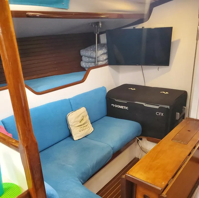Slide: The Image of Cozy interior of 1984 Beneteau First 42 sailboat with blue seating and TV. - 37