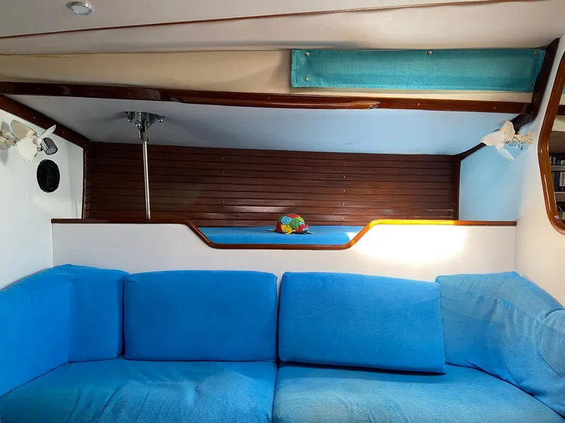 Slide: The Image of Interior of 1984 Beneteau First 42 sailboat with blue seating and wooden accents. - 44