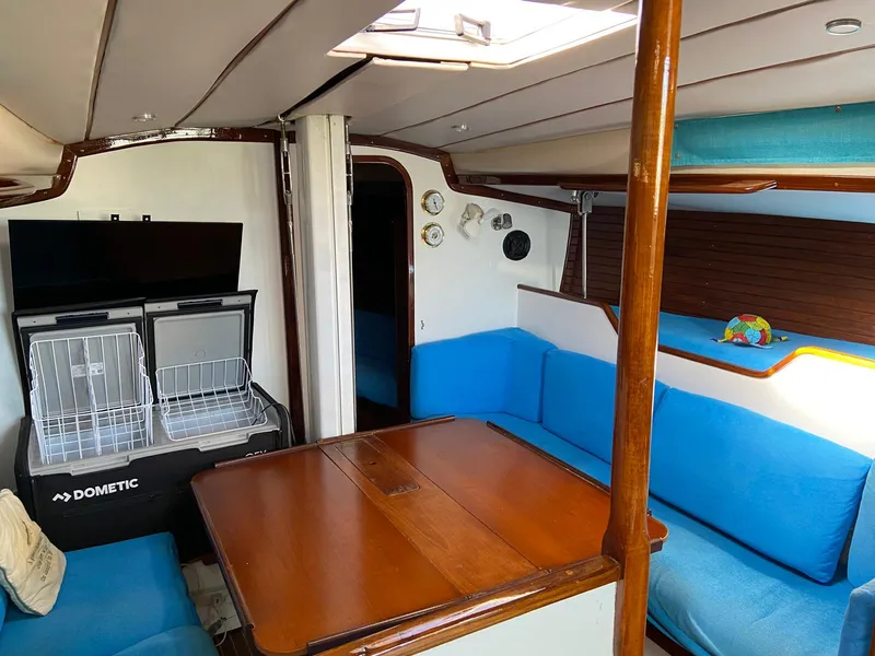 Slide: The Image of Interior of 1984 Beneteau First 42 sailboat with blue seating and wooden table. - 45