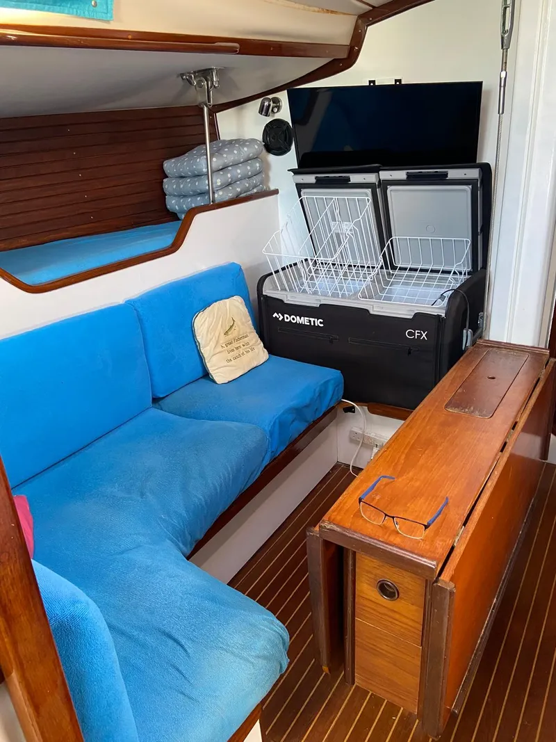 Slide: The Image of Interior of 1984 Beneteau First 42 sailboat with blue seating and wooden table. - 49